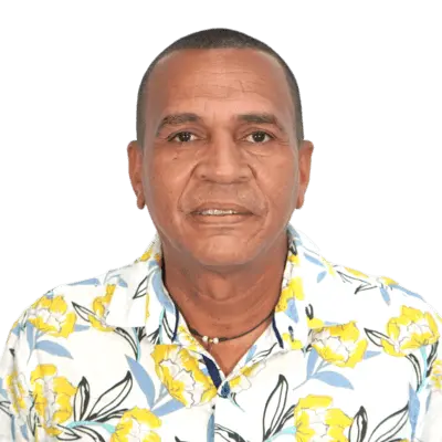 Mely Lindon Pedraza Fernández
mpedraza@staging6.uniguajira.edu.co
Profesional Grado 13, Hombre de cabello corto y oscuro, viste una camisa blanca con estampado de flores amarillas y hojas azules. Mira de frente a la cámara sobre un fondo blanco, con expresión seria y un collar negro alrededor del cuello.