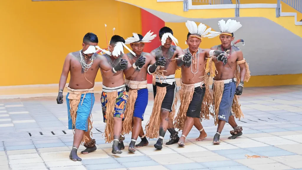 Grupo de 6 hombres jóvenes de la cultura Tikuna, haciendo una danza representativa.