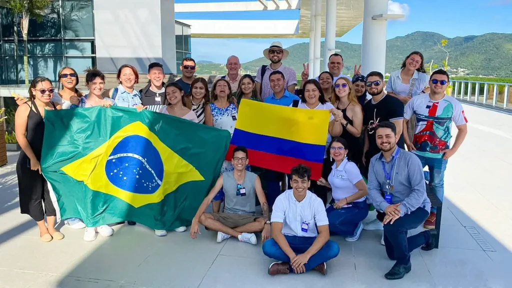 Grupo de personas entre jóvenes y adultas sosteniendo dos banderas de, una de color amarillo, azul y rojo (Colombia) y la otra bandera de color verde con amarillo con estrellas en el centro (Brasil).