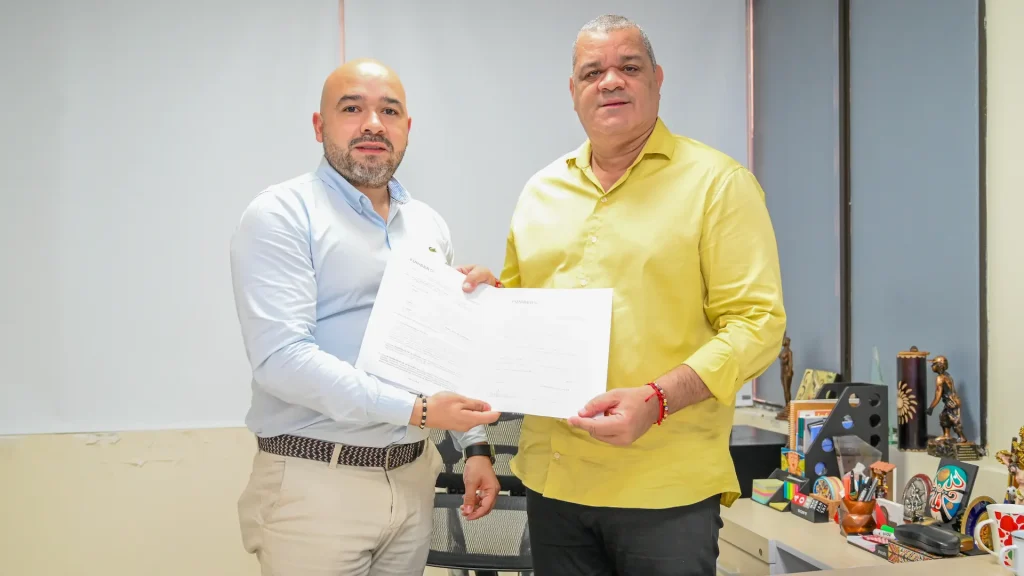 Dos hombres adultos muestran un papel del convenio firmado a la cámara.