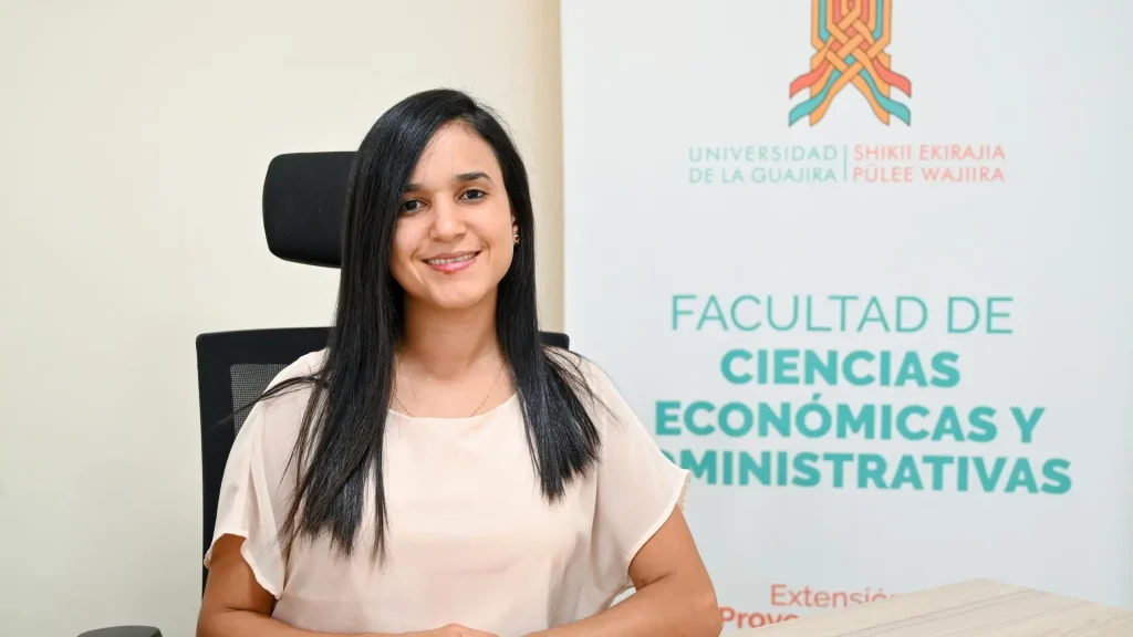 Mujer joven sonriente y sentada frente a un escritorio