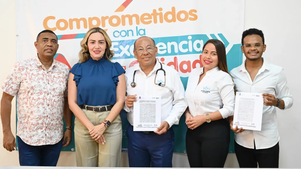 Cinco personas de pie posando para una foto, dos de ellos sostienen un papel en sus manos.