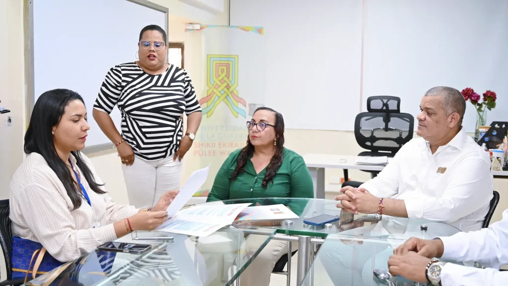 Cuatro personas socializando una temática, tres de ellos sentados y una sola de pie.
