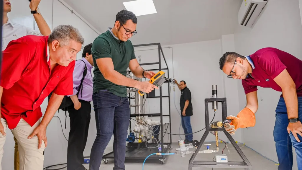 Un grupo de hombres adultos y jóvenes observando la planta que produce energía limpia
