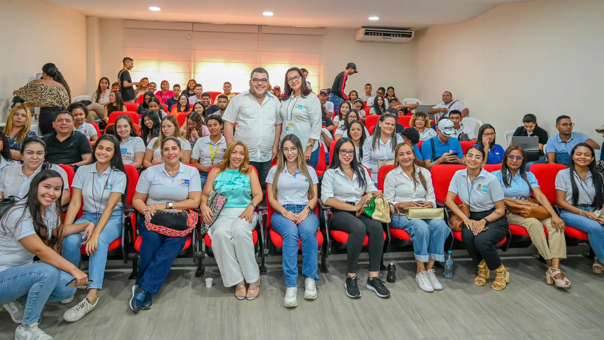 Grupo grande de personas posa para una foto al interior de un salón.
