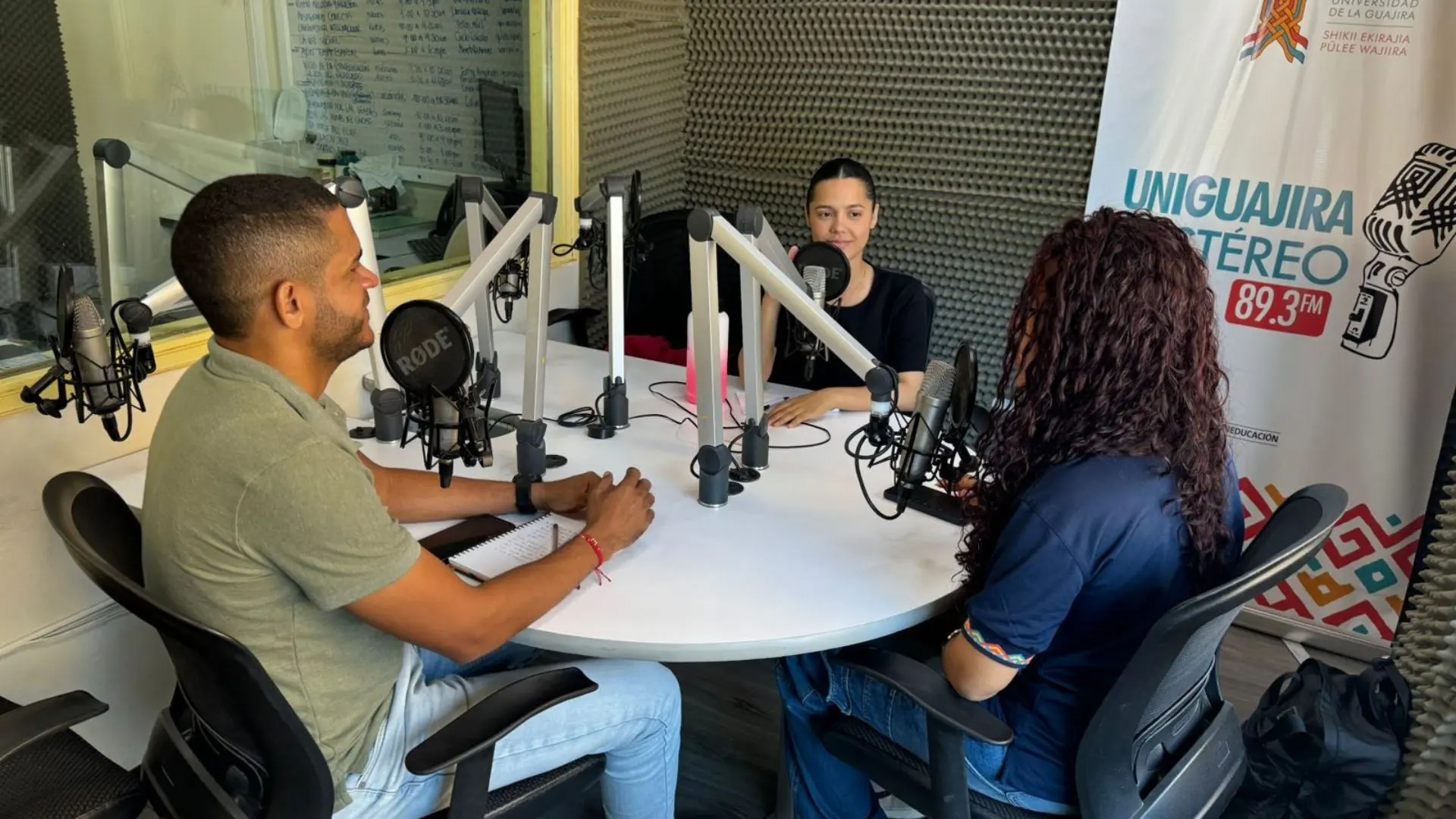 Tres personas adultas en una cabina de radio teniendo una conversación