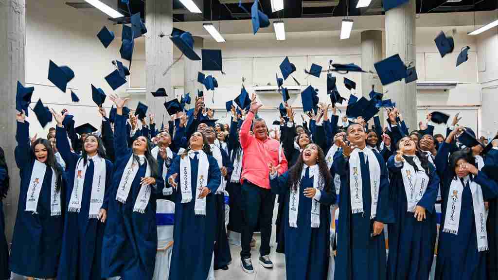 Estudiantes graduados de la Universidad de La Guajira celebrando en una ceremonia. El rector de la universidad, vestido de camisa salmón, se encuentra en el centro.