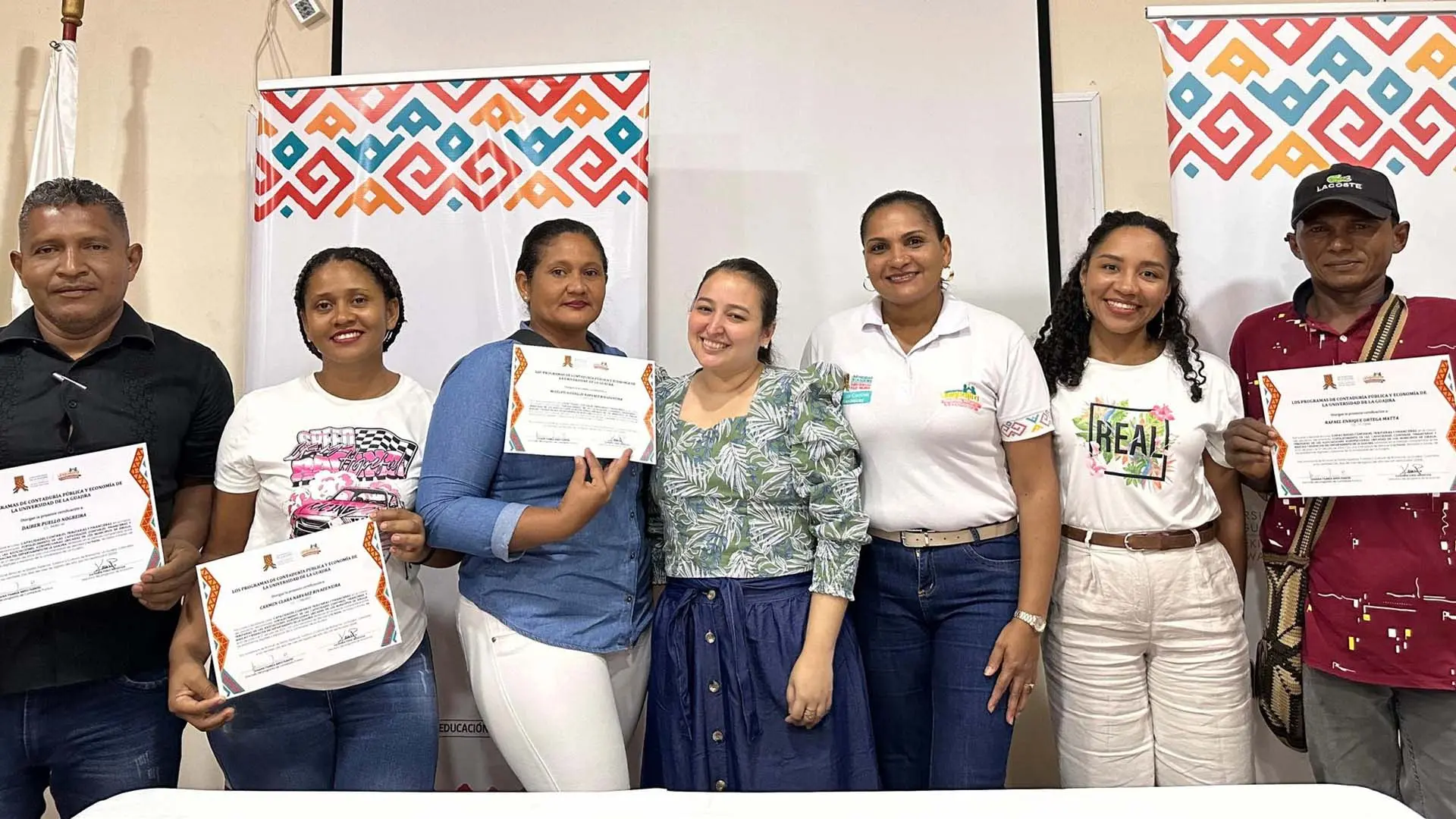 Grupo de personas entre hombres y mujeres de distintas edades sostienen certificados en reconocimiento a una labor.