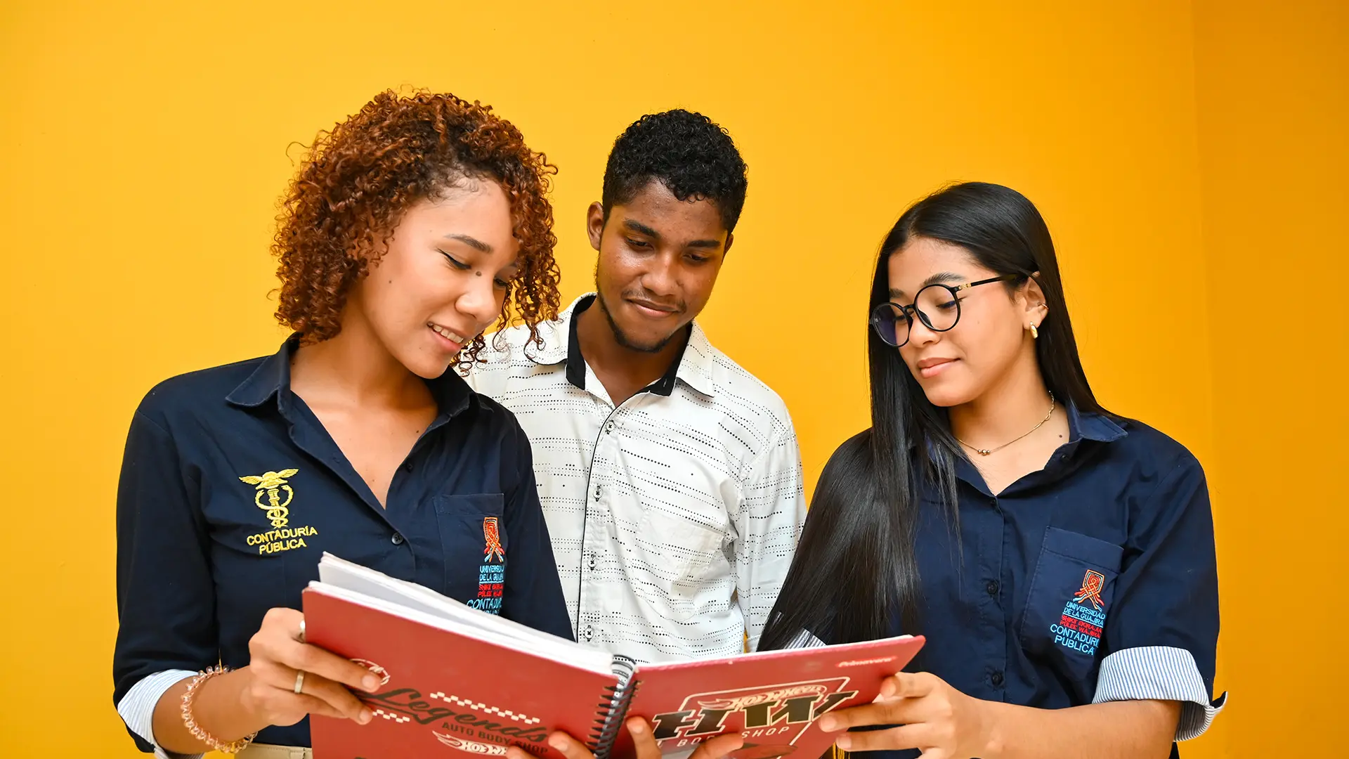 Estudiantes de Contaduría Pública de Uniguajira colaboran y comparten ideas mientras revisan sus apuntes, demostrando trabajo en equipo y compromiso con su formación académica.