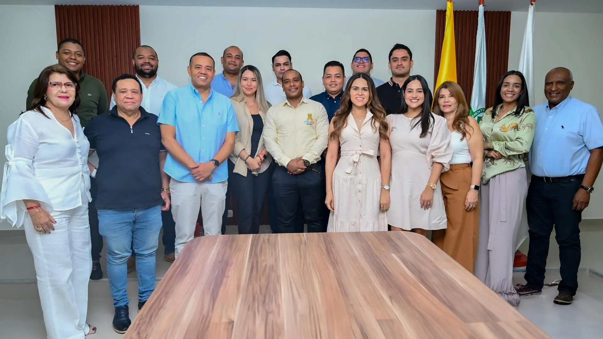 Un grupo de directivos, representantes institucionales, docentes, de pie. Al fondo banderas.