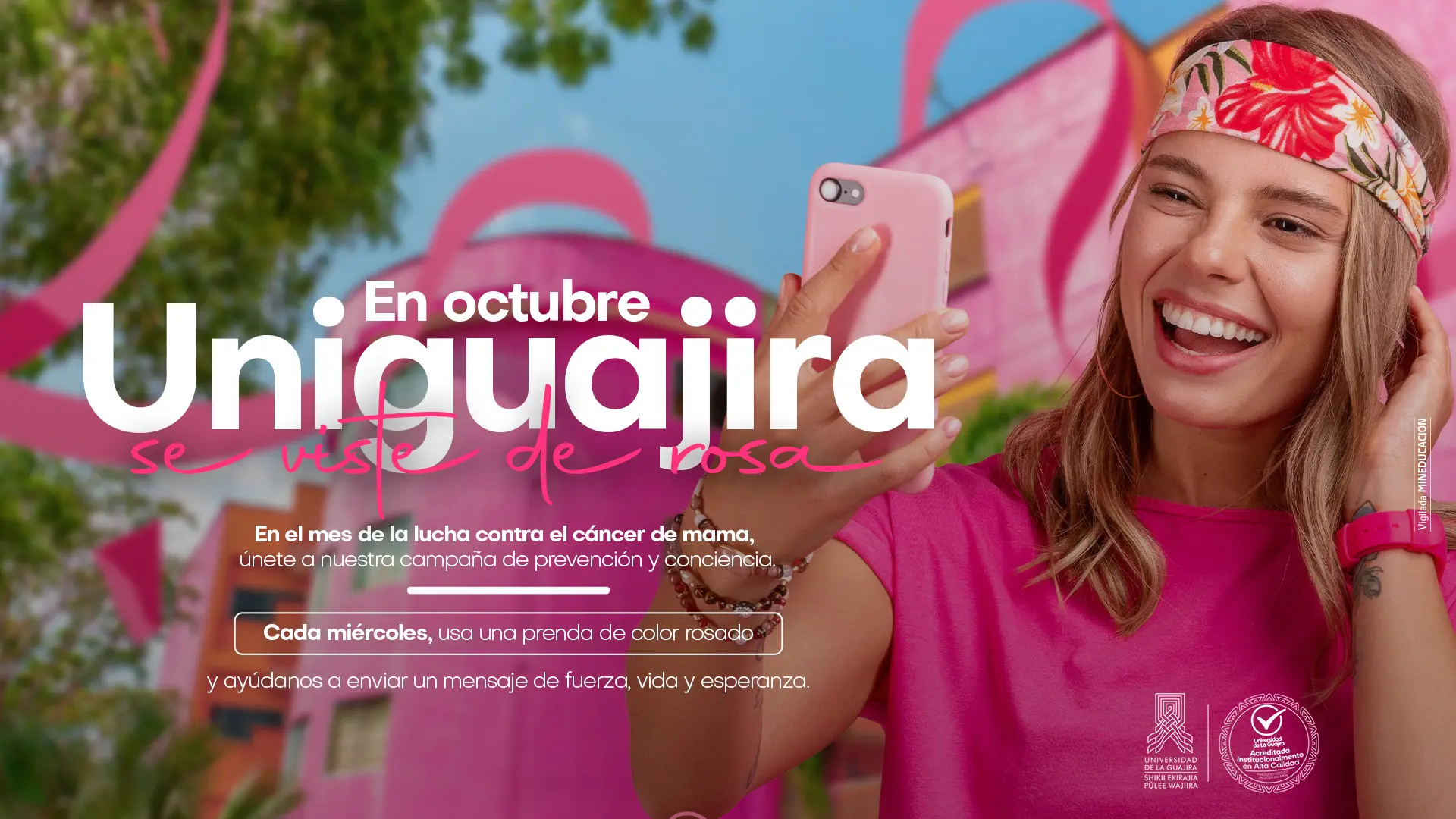 Joven sonriente con camiseta rosada frente a listones rosas. Texto: “En octubre, Uniguajira se viste de rosa. Cada miércoles usa una prenda rosada y únete a la campaña contra el cáncer de mama.”