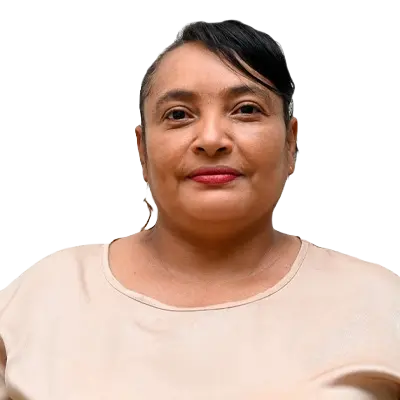 Jeidis Martínez Galvis Apoyo administrativo,retrato de una mujer de pie, mirando al frente con expresión serena. Lleva una blusa beige de manga corta y pendientes dorados, con el cabello recogido y un mechón hacia un lado.