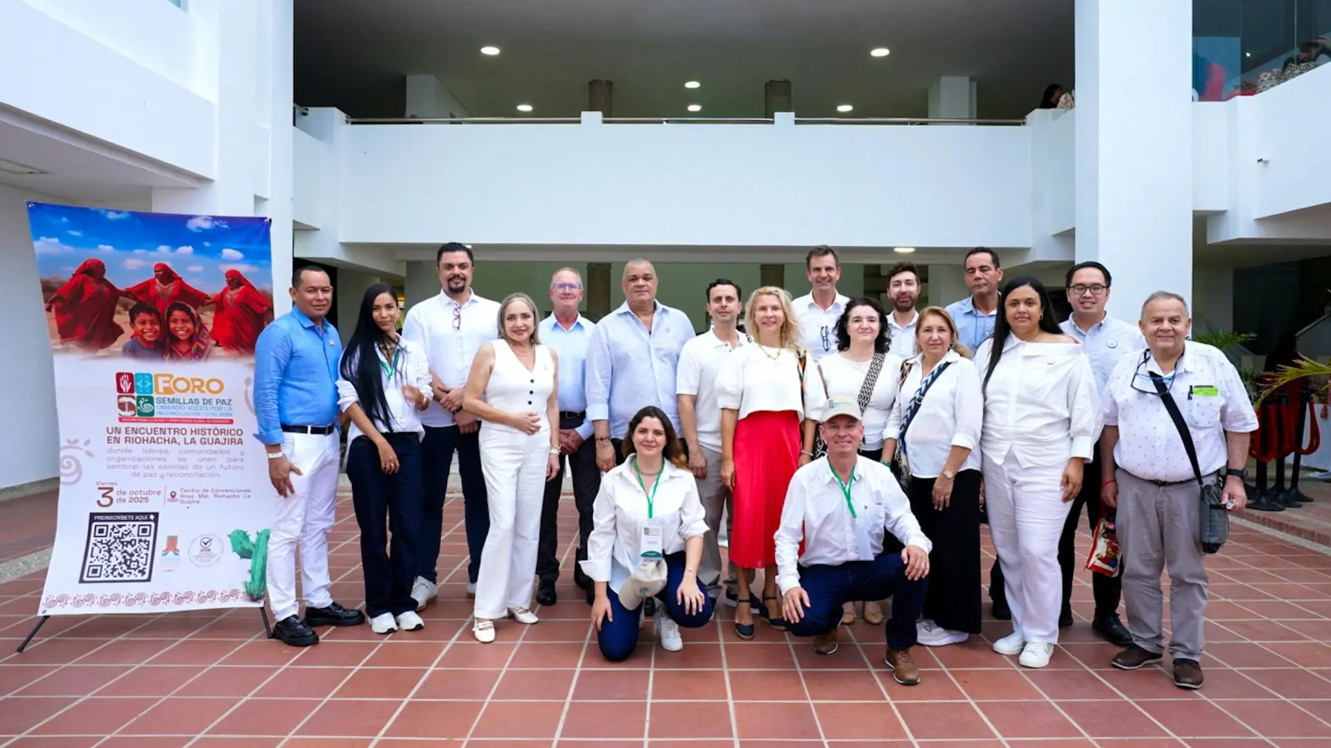 Grupo de personas posando para una foto oficial durante el Foro “Semillas de Paz” realizado en Riohacha, La Guajira. Detrás de ellos se observa un cartel del evento con información y logotipos institucionales.