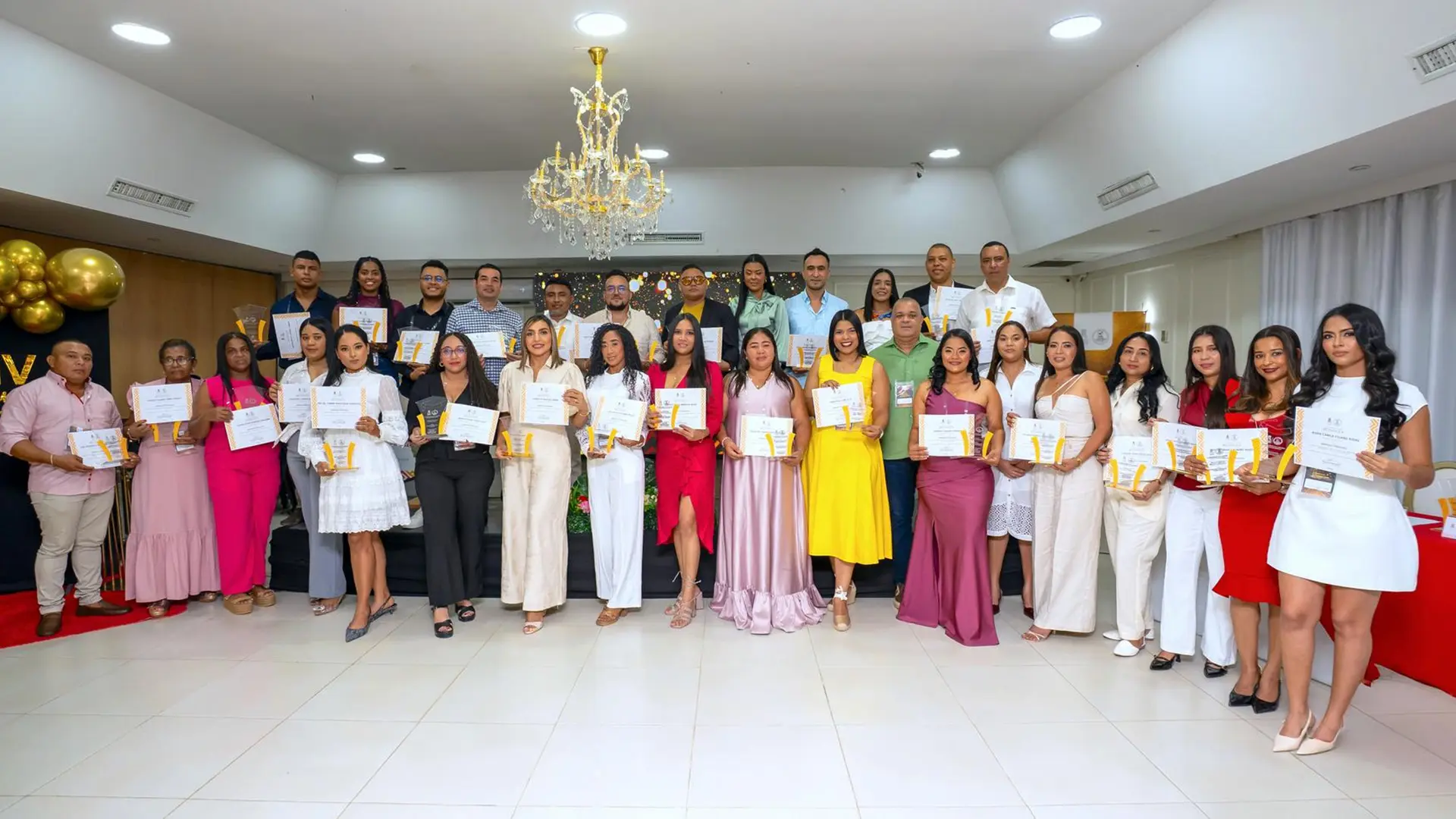 Cuatro personas posan frente a un escenario sosteniendo dos cheques simbólicos de capital semilla por valor de $2.000.000 cada uno, otorgados a graduados emprendedores durante el Encuentro de Graduados “Raíces que Conectan”.