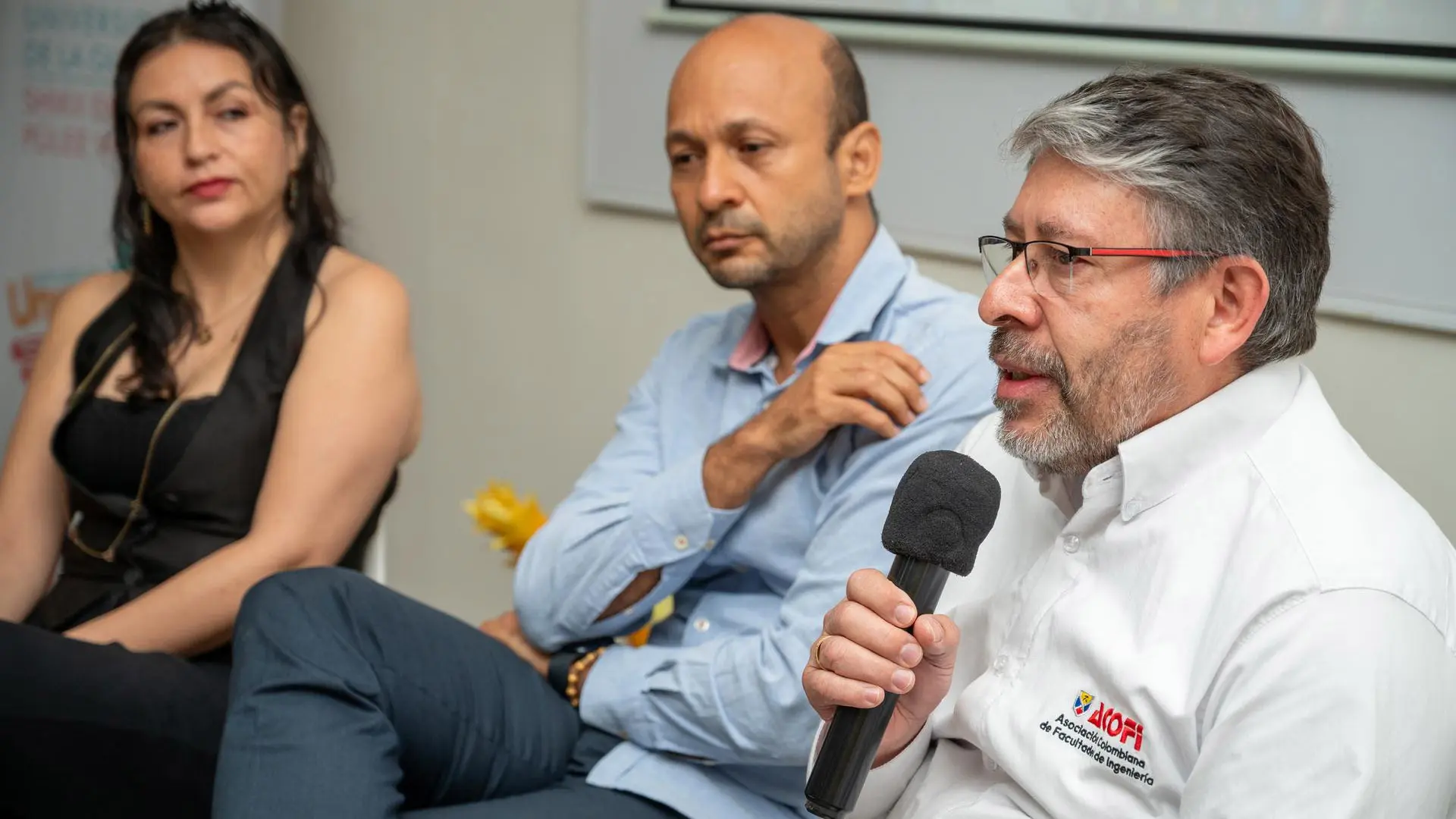 Miembro de ACOFI participa como panelista en un evento académico, mientras otros invitados atienden su intervención.