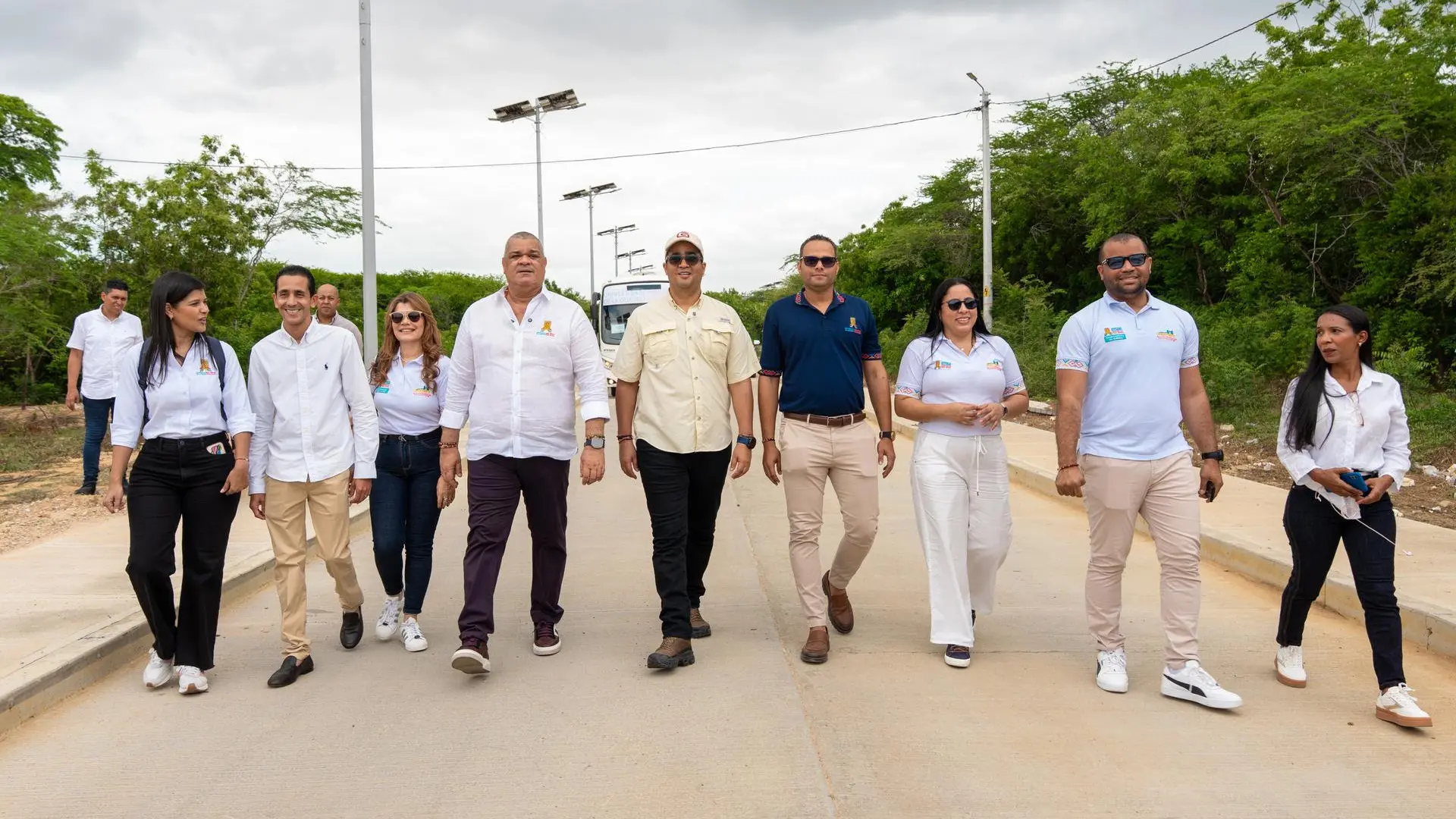 Rector, gobernador y equipo directivo de Uniguajira caminan por la nueva vía interna rodeada de vegetación y luminarias solares. La imagen muestra un recorrido institucional al aire libre, en el que las autoridades conversan mientras inspeccionan las obras o infraestructura del campus.
