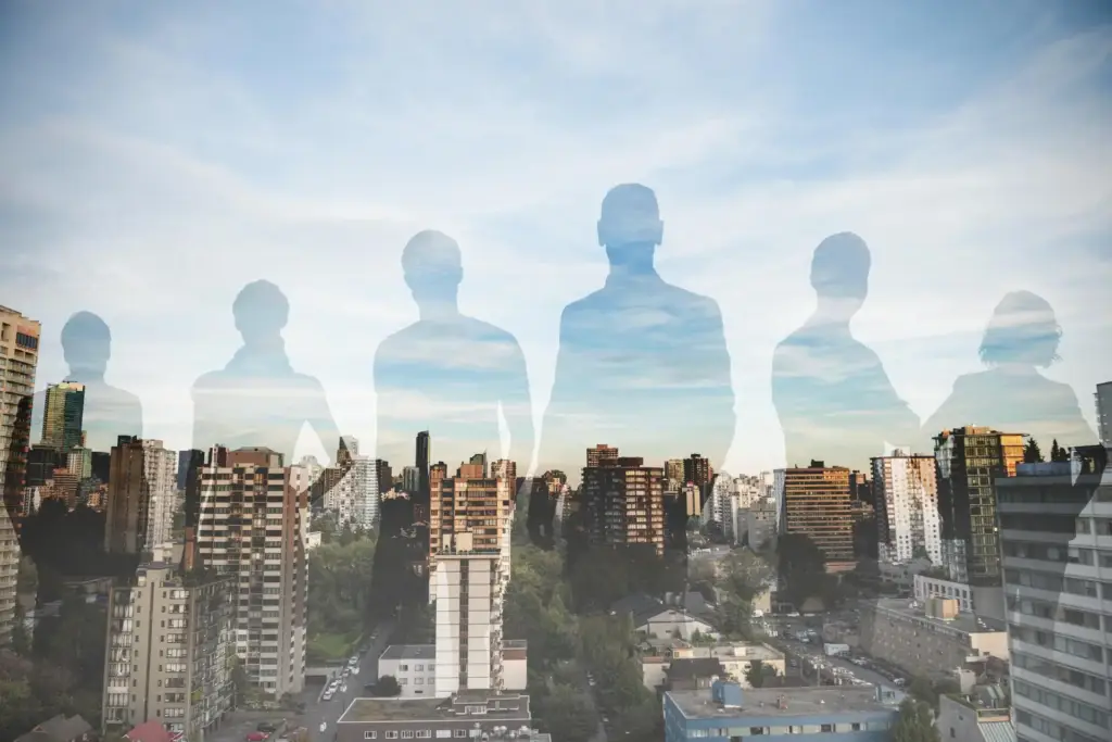 Ilustración conceptual de cinco siluetas de personas superpuestas sobre el horizonte de una ciudad moderna, representando diversidad, trabajo en equipo, liderazgo o comunidad en un entorno urbano.