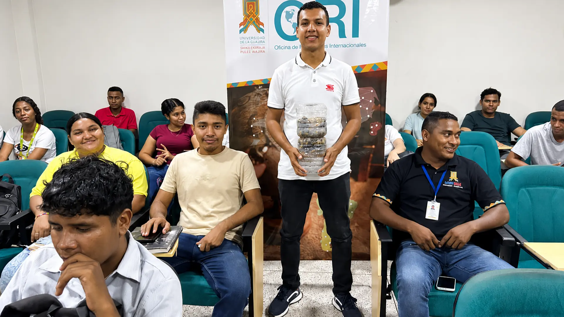 Estudiantes participan en una actividad de intercambio académico en la Oficina de Relaciones Internacionales de Uniguajira; uno de ellos sostiene un objeto artesanal.