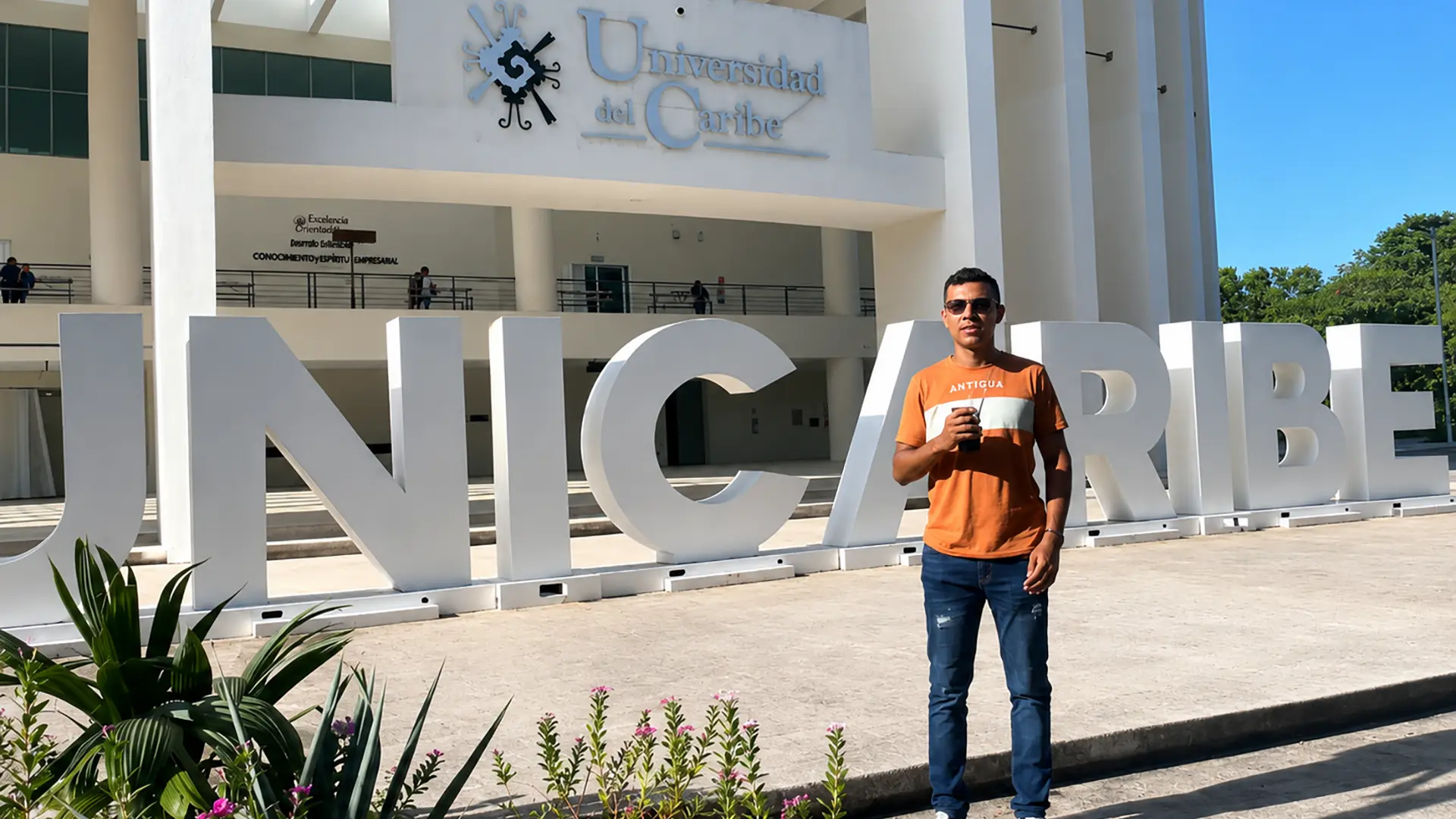 Estudiante posa frente a las instalaciones de la Universidad del Caribe, durante una experiencia de movilidad académica internacional.